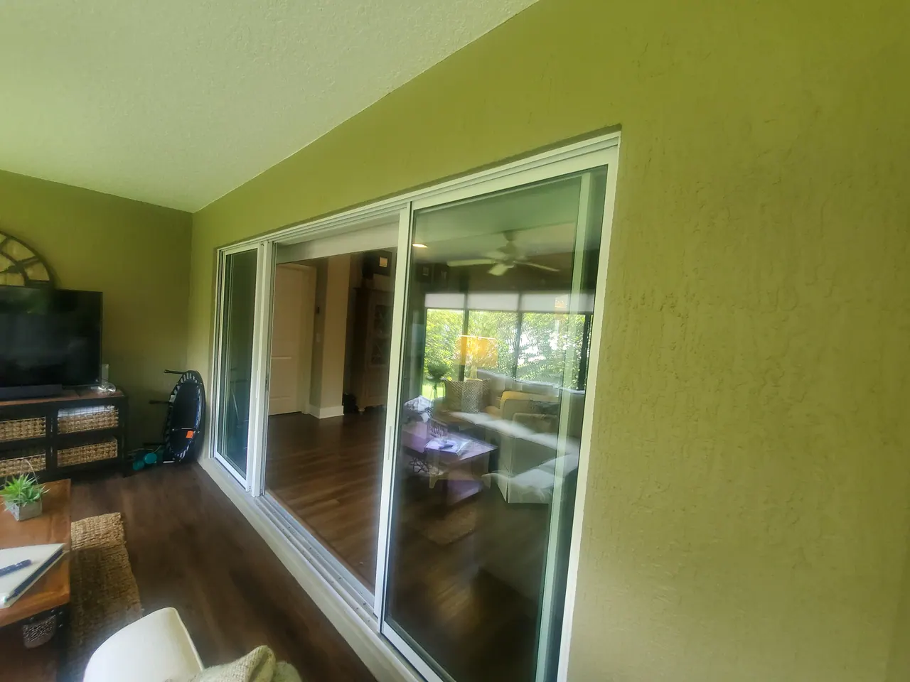 Wide sliding glass doors connecting a green-walled enclosure to the home.