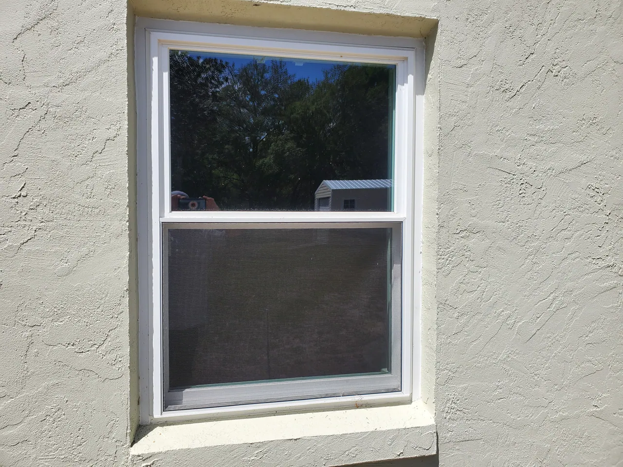 White-framed window set into a light textured stucco exterior wall.